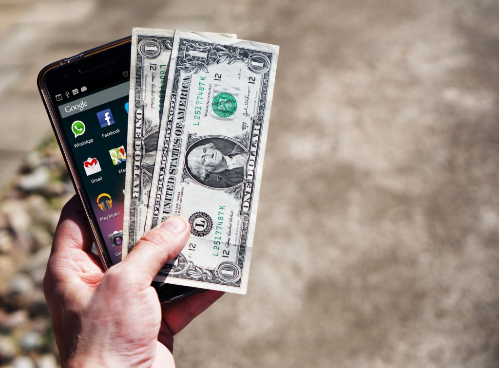 Person Holding Black Android Smartphone and 2 U.S. Dollars